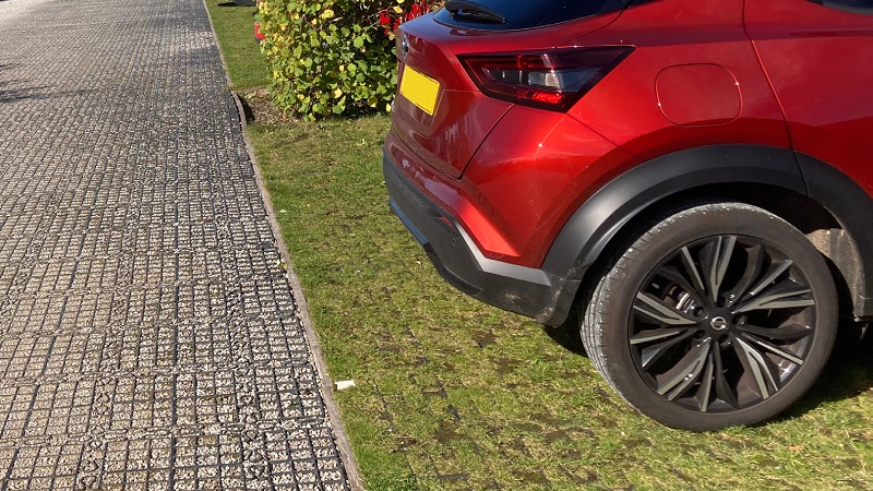 Image of a parking area covered in grass while the main path uses gravel